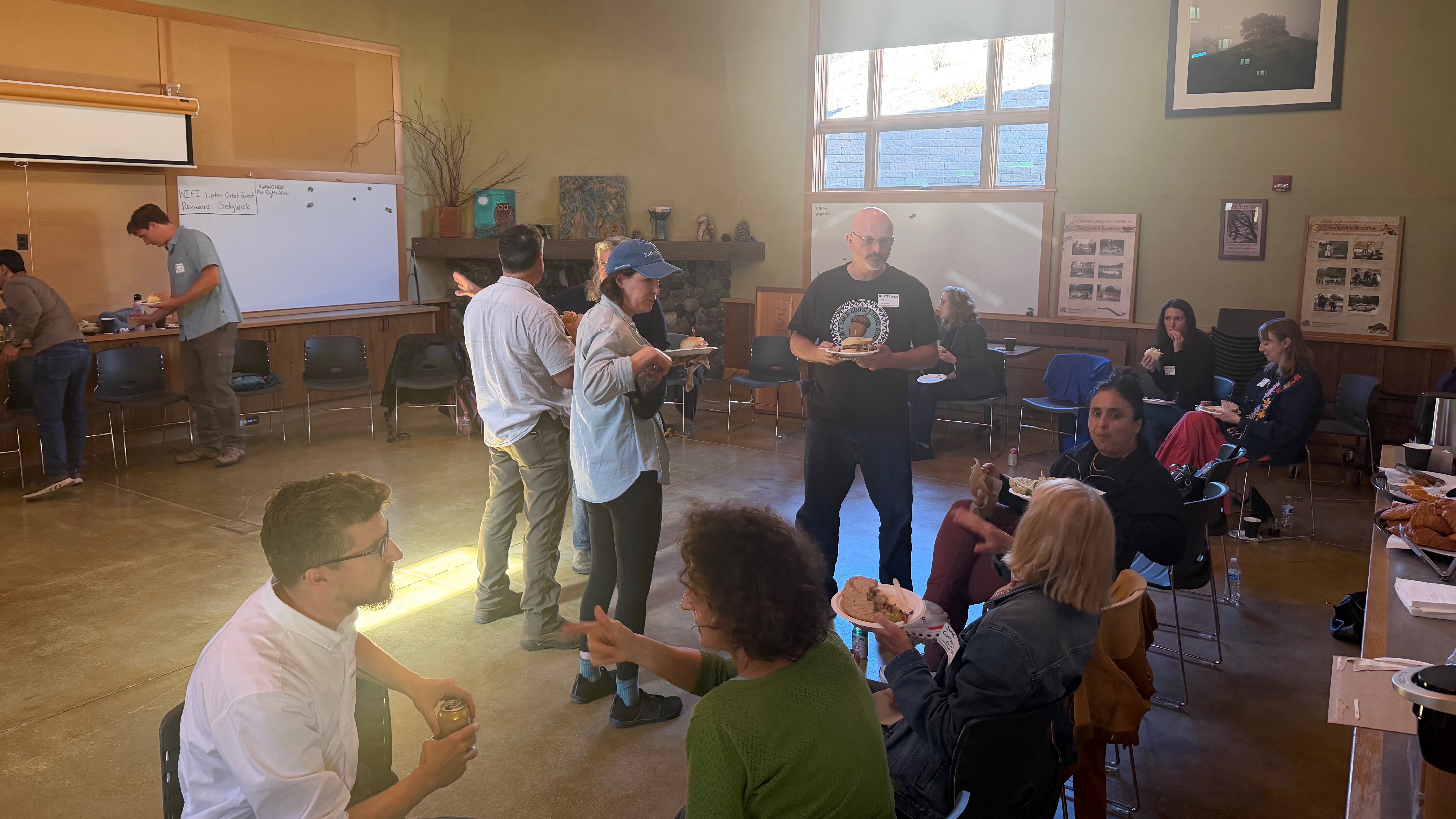 Faculty and staff talk and laugh while seated at an outdoor picnic table for lunch at the Sedgwick Reserve.