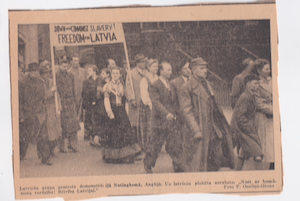 A historical black and white newspaper clipping from circa 1950 showing a group of Latvians protesting in Nottingham, England. They are carrying a sign that reads "DOWN WITH COMMUNIST SLAVERY! FREEDOM FOR LATVIA." Some individuals are wearing national dress.