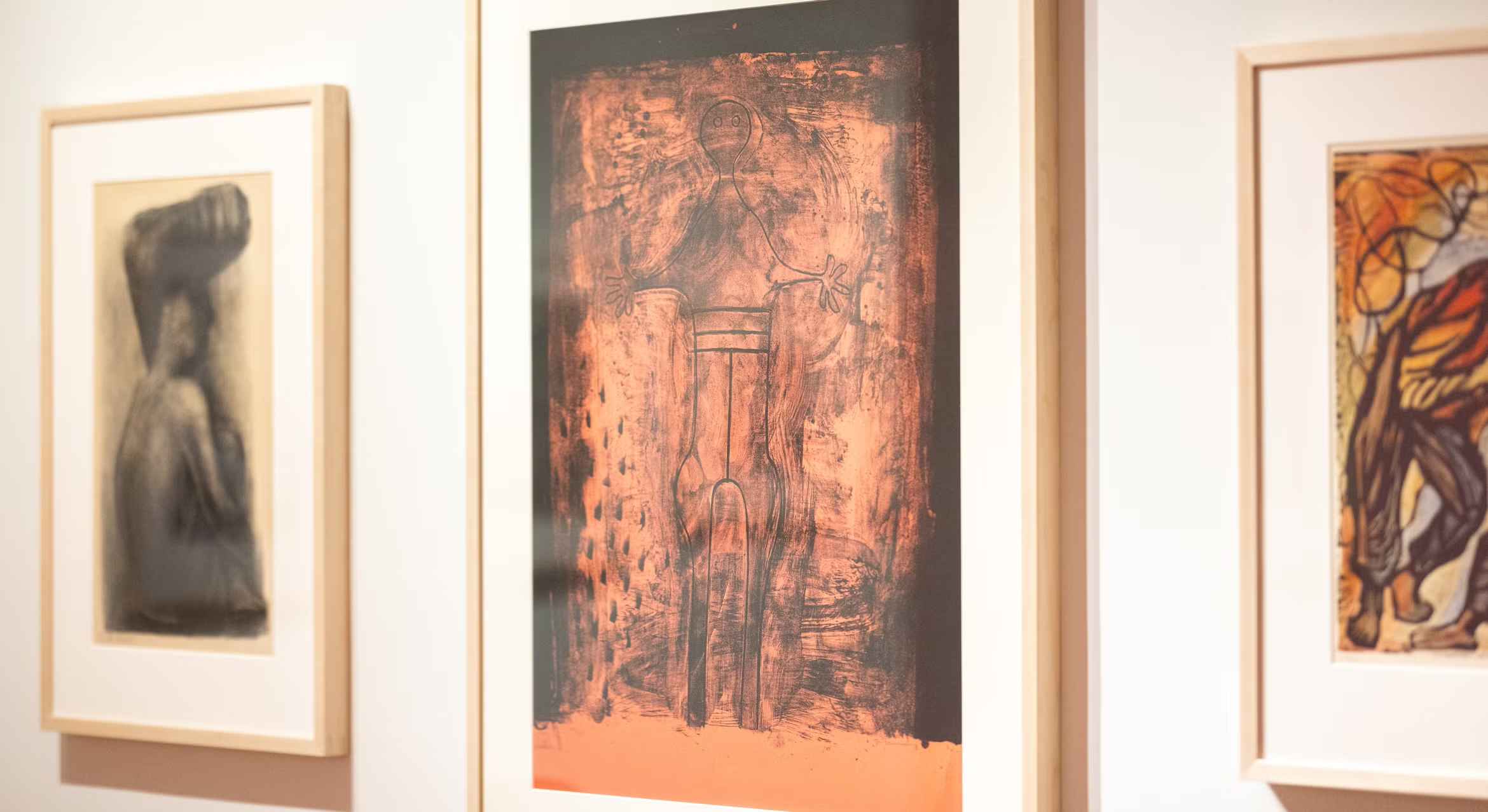 A framed Mexican print with orange and black tones depicting a stylized figure hangs on a white gallery wall at the AD&A Museum.