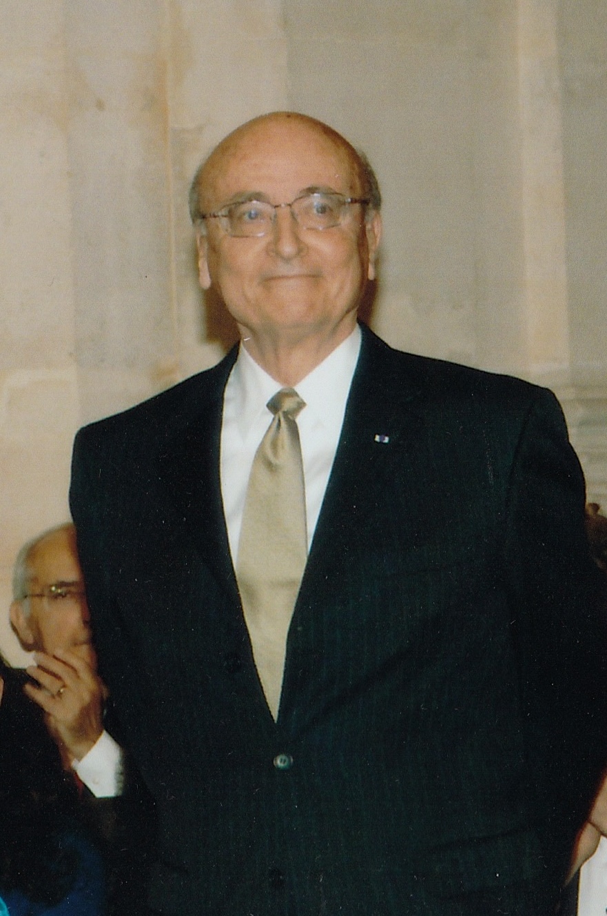 Ronald W. Tobin wearing glasses, a dark suit and a light-colored tie.